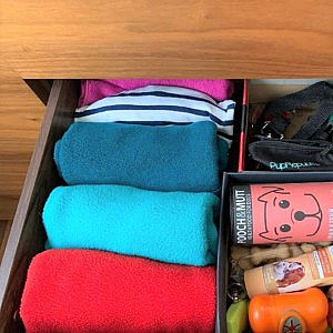 an organised drawer of folded pet jackets and treats
