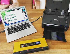 a photo scanner, laptop and box of photos on a desk